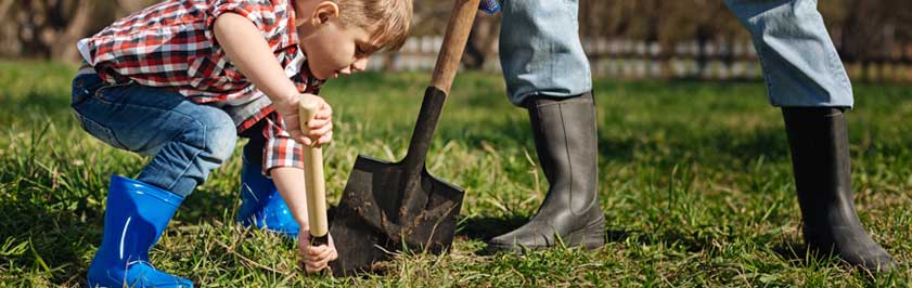 Adult and child digging a hole with shovels