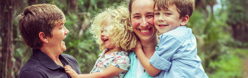 two women each holding a child outside