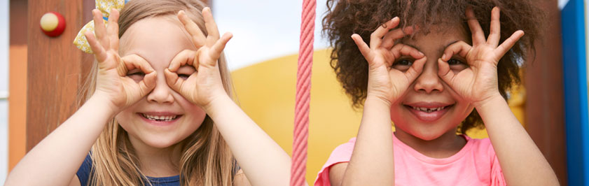 two children on a playground looking through their hands