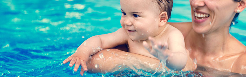 Woman holding baby in a swimming pool