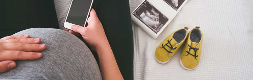 Pregnant woman sitting in a chair holding a cell phone 
