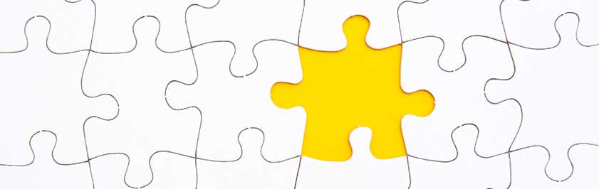 Yellow jigsaw puzzle piece surrounded by white jigsaw puzzle pieces